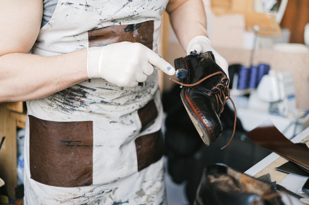 Craftsperson applying edge finish to a black leather dress shoe in the Becalor atelier
