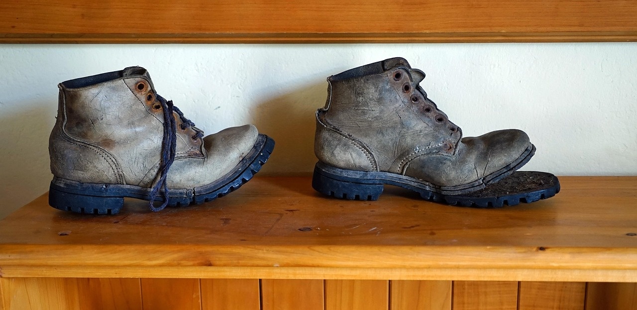 Heavily worn work boots with separated soles before restoration