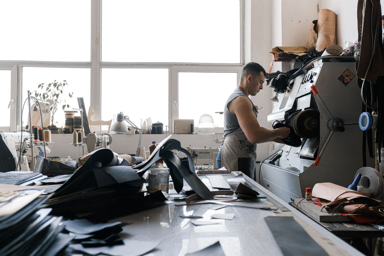 Bright Australian workshop with a craftsman finishing a shoe beside leather materials