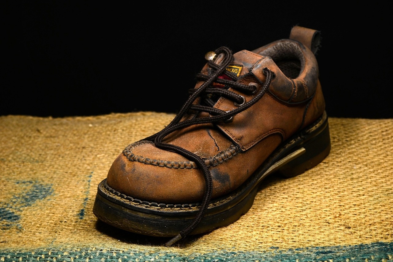 Worn brown leather shoe with cracking and staining before restoration