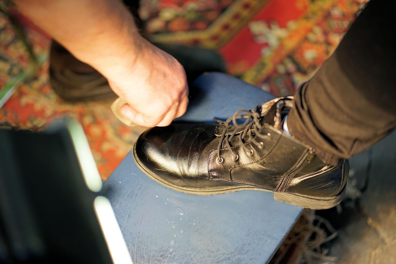 Hand polishing the toe of a black leather boot on a workshop stand
