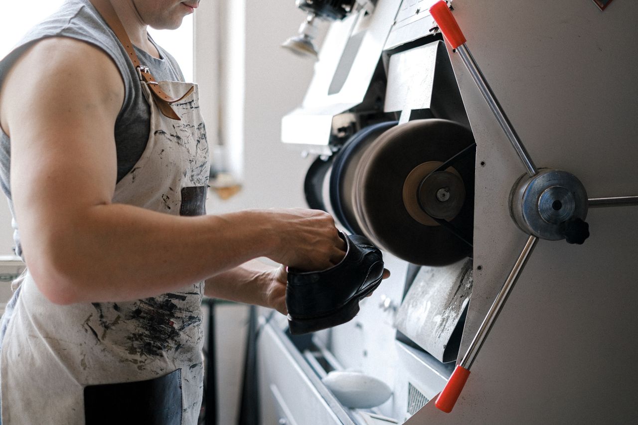 Cobbler finishing a black leather shoe on a professional polishing machine