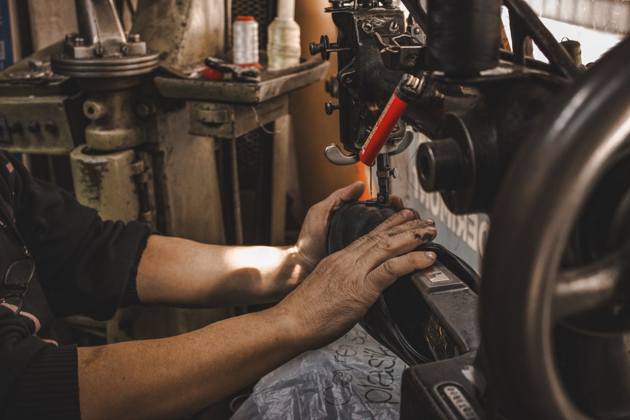 Experienced hands guiding a leather shoe through an industrial stitching machine